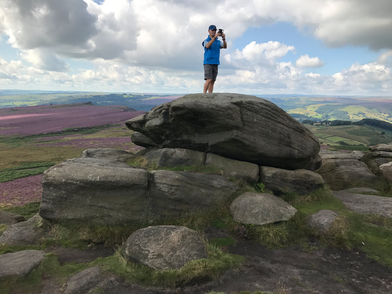 Photographer standing on gritstone boulders at Higger Tor