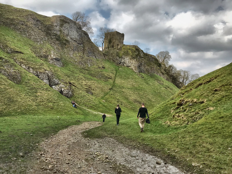 Walkers passing Peveril Castle, in Cave Dale, Castleton, Peak District