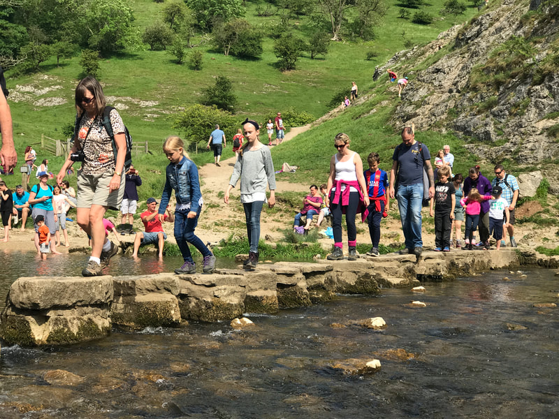 People walking across the stepping stone at Dovedale